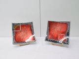 two small red dishes on a white table