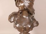 bronze bust of a woman with a hat on her head