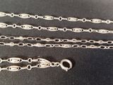 three silver chains are laying on a black surface