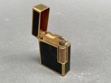 an image of a gold and black lighter sitting on top of a table