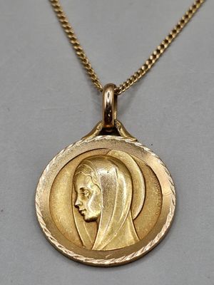 a close up of a gold necklace with a woman ' s face on it
