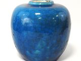 un vase bleu posé sur une surface blanche