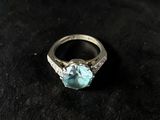 a close up of a ring with a blue stone on a black surface