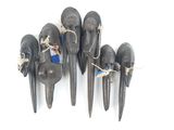 six têtes d'éléphant noires sculptées, suspendues à une corde sur un mur blanc