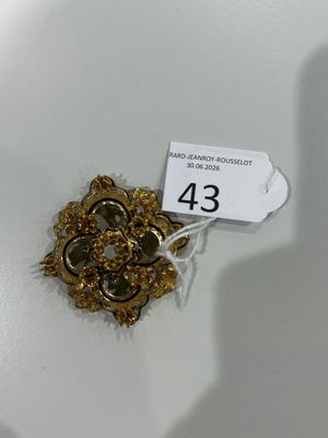une broche en or posée sur une assiette blanche, avec une étiquette de prix