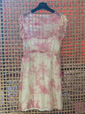 a pink and white dress on a hanger in front of a wall