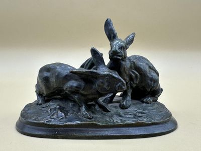sculpture représentant trois lapins sur un rocher au bord d'un ruisseau