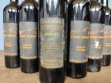 several bottles of wine are lined up on a wooden table