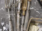 a lot of silverware on a table with other silverware