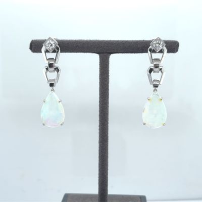 a pair of oplite and diamond earrings on a stand