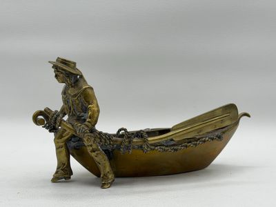 figurine en bronze représentant un homme assis dans un bateau avec un chien