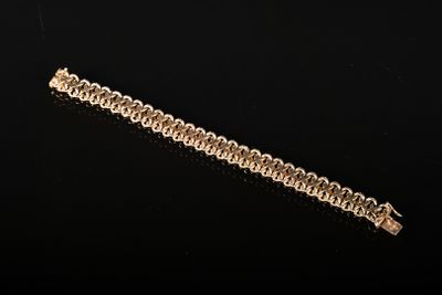 gros plan d'un bracelet en chaîne en or sur une surface noire