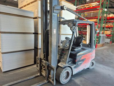 a forklift in a warehouse with stacks of pallets in the background