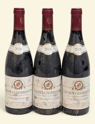 trois bouteilles de vin rouge posées l'une à côté de l'autre sur une surface blanche