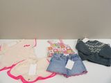 several children ' s clothes are lined up on a white table
