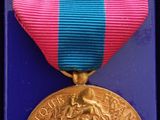 un ruban violet et bleu surmonté d'une médaille d'or