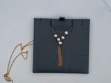 collier composé de perles et d'une chaîne en or, présenté sur une assiette blanche