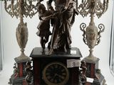 une statue représentant une femme tenant une horloge devant un lustre