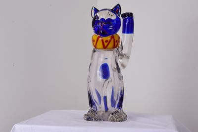 une figurine de chat en verre posée sur une table blanche