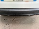 the rear bumper of a white car with a blue stripe