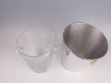 a silver bucket and a glass on a white table