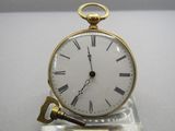 a gold clock with roman numerals and a key