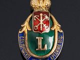 an image of a gold and green enamel badge with a crown on it