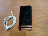 un téléphone portable posé sur une table, branché à un chargeur