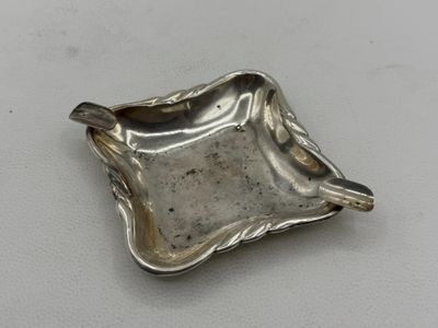 a silver plate with a spoon on it sitting on a white surface