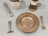 a silver plate and silverware on a table with a bottle of wine