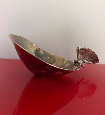 un bol rouge orné d'un papillon, posé sur une table rouge