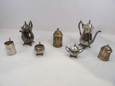 un ensemble de théières en argent et d'autres objets posés sur une surface blanche