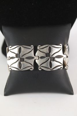 un gros plan d'un bracelet en argent posé sur un coussin noir