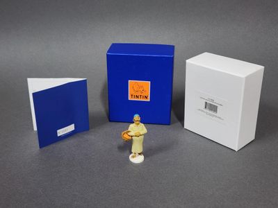 une figurine représentant un homme tenant une raquette de tennis devant une boîte