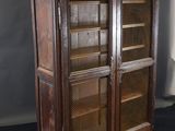 an old wooden bookcase with glass doors on a black surface