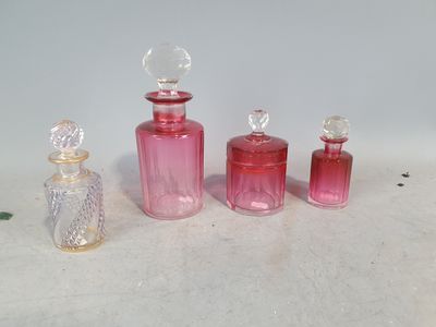 trois petites bouteilles en verre roses posées les unes à côté des autres sur une surface blanche