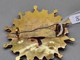 a close up of a gold brooch with a tag on it