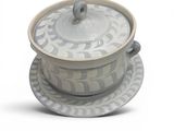 a white and gray bowl and saucer sitting on a plate