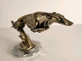 statue of a greyhound dog running on a base on a white surface