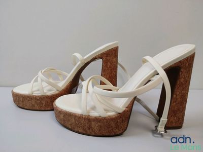 une paire de sandales blanches à talons hauts posées sur une surface blanche