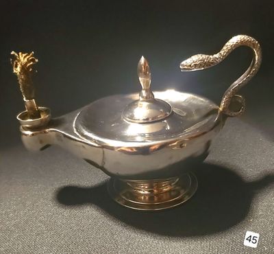 an antique silver plated teapot with a snake handle on a black surface