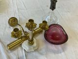a pink glass bowl and a brass candle holder on a white sheet