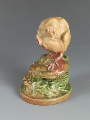 une figurine représentant un oiseau perché sur un tas de feuilles