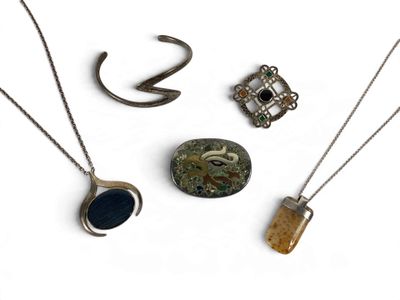 trois colliers différents et une bague posés sur un fond blanc