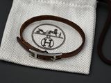 leather bracelet with a silver clasp on a white cloth bag