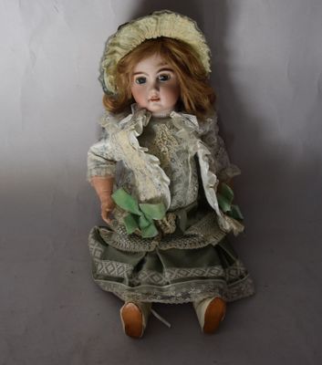une poupée assise par terre, vêtue d'une robe et d'un chapeau