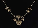 a silver necklace with flowers and leaves on a black background