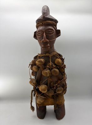 an old wooden figurine of a man with a hat and a bunch of nuts on his head