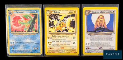 Trois cartes Pokémon différentes sont posées sur une table.