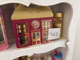 a shelf with a doll house and other items on it